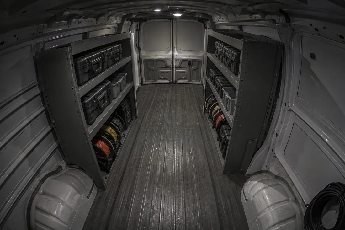 Cargo area of a service van with tool cases on locking shelves